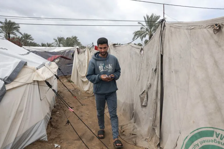 Gaza families survive in darkness, relying on drained phones for light.